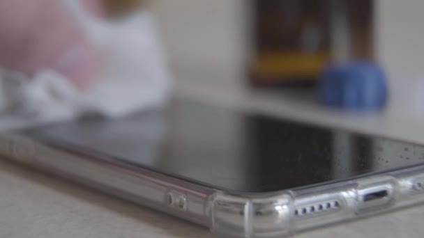 Male Caucasian hand rubbing phone screen with white sanitizer napkin. Close-up of unrecognizable man wiping smartphone with disinfectant. Covid-19, hygiene, coronavirus, quarantine. — Stock Video