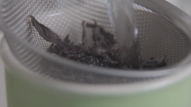 Detailní záběr vody tekoucí po čajových lístcích v šálku. Vaří se horký nápoj. Aromatický ranní nápoj. — Stock video