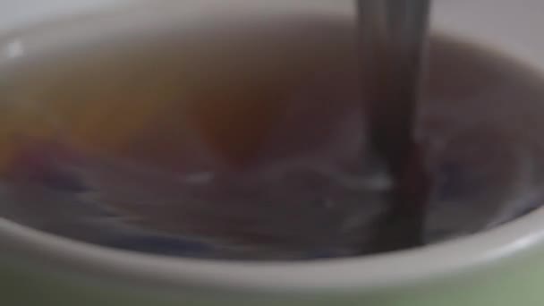 Extreme close-up του κουταλάκι του γλυκού ανάμειξη ζεστό ρόφημα στο κύπελλο. Άγνωστο άτομο που διαλύει ζάχαρη στο τσάι. Ποτά, ζυθοποιία, κουζίνα, τρόπος ζωής. — Αρχείο Βίντεο