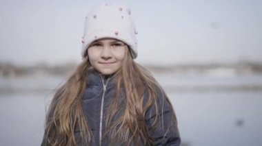 Nehir kıyısında açık havada duran esmer bir kızın portresi. Beyaz sevimli bir çocuk göl kıyısındaki kameraya bakıyor. Çocukluk, eğlence, güzellik, yaşam tarzı..