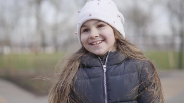 Portret van een mooi blank brunette meisje dat buiten lacht en praat. Close-up gezicht van vrolijk schattig kind genieten van zonnige dag in het park. Vrije tijd, levensstijl, geluk. — Stockvideo