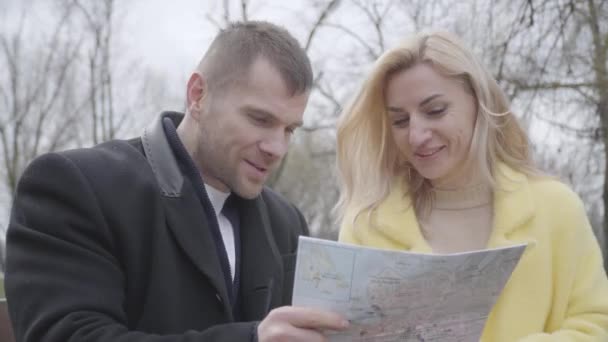 Close-up van een blanke man en vrouw die kaart onderzoeken en praten. Portret van een positief glimlachend koppel dat buiten reist. Vreugde, vrije tijd, levensstijl, toerisme, reis. — Stockvideo
