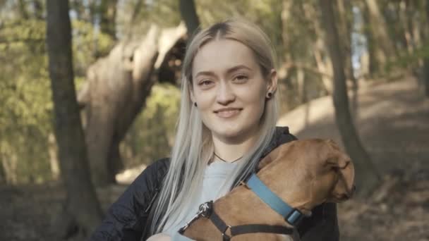 Närbild av charmig blond vit kvinna med husdjur ler mot kameran. Porträtt av ung attraktiv flicka njuter solig dag i parken med tax på händerna. Livsstil, fritid, glädje. — Stockvideo