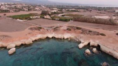 Terkedilmiş kahverengi kıyı şeridi olan kristal berrak turkuaz bir göl. Kıbrıs 'taki Akdeniz tatil beldesinin havadan görünüşü. Deniz manzarası, doğa, turizm, seyahat.