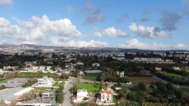 Kıbrıs 'ta mavi gökyüzü altındaki muhteşem turistik tatil beldesinin insansız hava aracı manzarası. Akdeniz 'in yanındaki tepelerdeki lüks binaların hava manzarası. Lüks turizm, doğa, manzara.