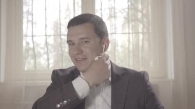 Kahverengi gözlü, neşeli esmer adamın yakın plan çekimi. Kablosuz sohbet ve nargile içerek insanlara veda ediyor. Covid-19 'da dinlenen kendinden emin beyaz bir gencin portresi. S-log-2 ProRes 422 Merkez