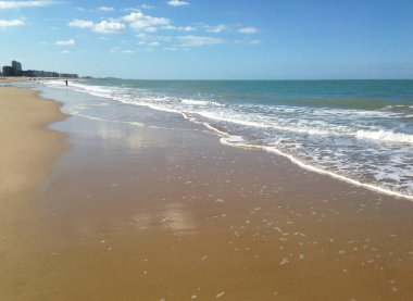 Belçika 'nın Ostende şehrinde güneşli bir günde kumlu sahilden manzara. 