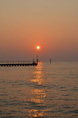 Adriyatik Denizi 'nin güzel kıyı şeridi. Lido di Jesolo sahilinde gün batımı. Denizde rıhtım