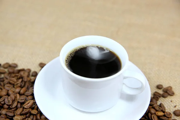 Café caliente con un fondo de granos de café —  Fotos de Stock