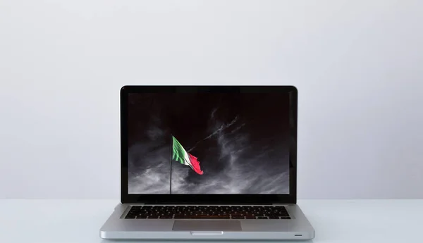Portatile aperto con immagine significativa della bandiera italiana sotto un cielo tempestoso — Foto Stock