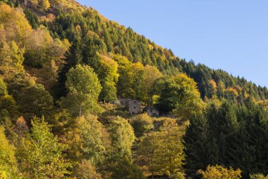 Bir dağın tepesine inşa edilmiş eski bir dağ köyü. Çan kuleleri, evler ve taş çatılar.