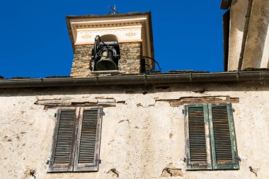 Bir dağın tepesine inşa edilmiş eski bir dağ köyü. Çan kuleleri, evler ve taş çatılar.