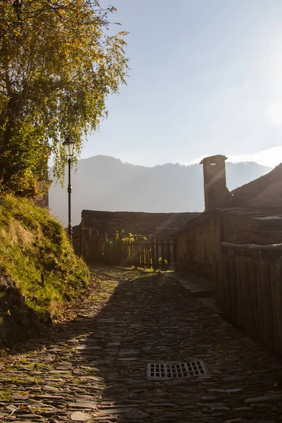 Gamla alpina byn byggd på toppen av ett berg. Klocktorn, hus och stentak — Stockfoto