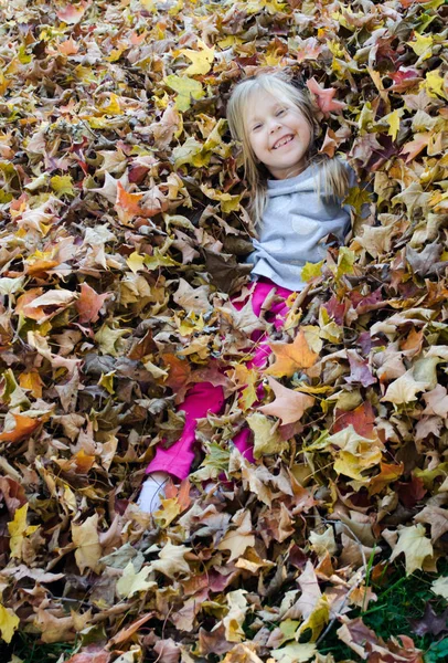 Sonbahar yapraklarındaki mutlu kız. — Stok fotoğraf