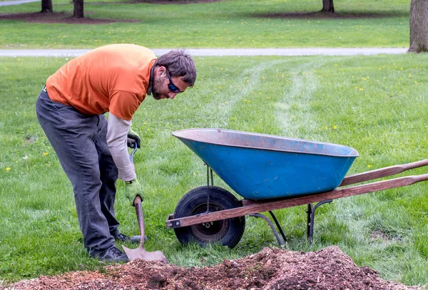 Arbeiter räumt mit Schaufel und Schubkarre Unrat weg — Stockfoto