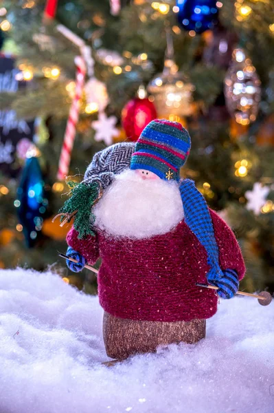 Старик Санта на лыжах держит мешок игрушек и крошечное дерево — стоковое фото