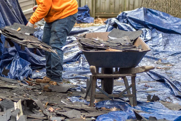 Arbetare fyller skottkärra med gamla bältros — Stockfoto