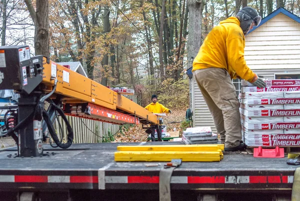 Trabalhadores descarregam telhas pesadas em uma correia transportadora — Fotografia de Stock