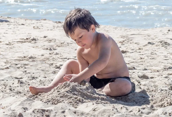 Ένα μικρό αγόρι χτίζει ένα κάστρο στην παραλία — Φωτογραφία Αρχείου