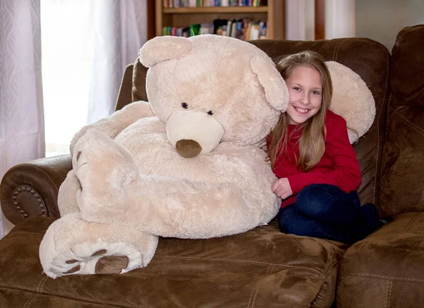 Girl and teddy bear on sofa — ストック写真