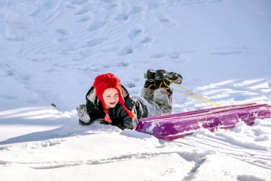 Küçük çocuk kızağından düşer.
