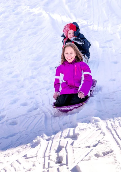 Crianças escorregando por uma colina de neve — Fotografia de Stock