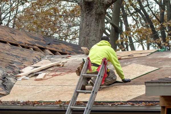 Un ouvrier répare un toit sur une vieille maison — Photo