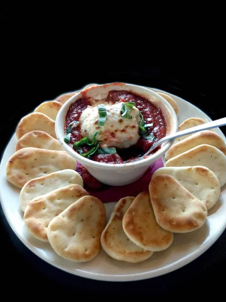 Creamy goat cheese fondue in a tangy red marinara sauce, with warm mini flat breads