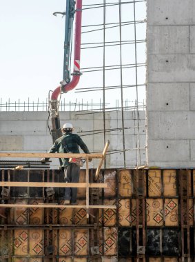 Grand Rapids Michigan Usa 8 Mart 2019; bir işçi bir inşaat sahasında çimento yapı inşa ederken iskele üzerinde duruyor