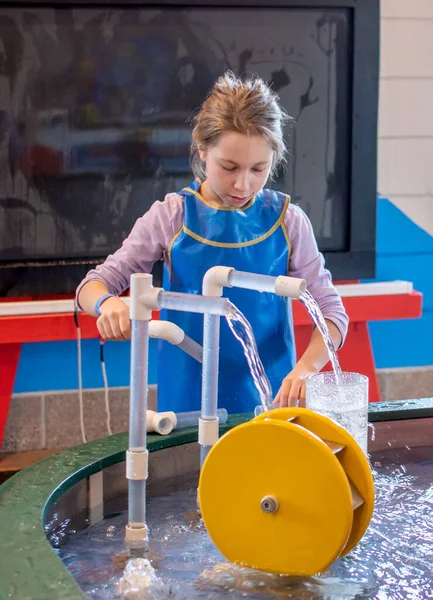 Молодая Девушка Узнает Вода Течет Направлять Играя Крытом Столе Водой — стоковое фото