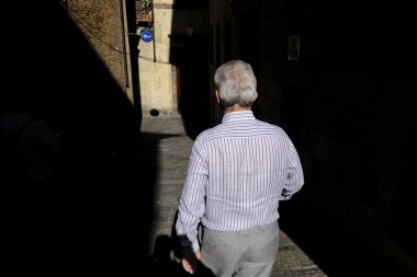 Yaşlı bir insan, 26 Ekim 2019 'da İtalya' nın Siena şehrinin tarihi merkezinde yürüyor..