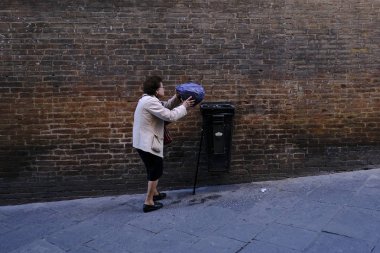 27 Ekim 2019 'da İtalya' nın Siena şehrinde bir kadın çöp tenekelerini boşalttı.