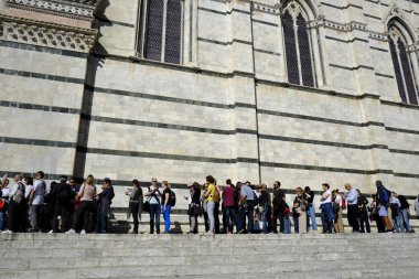 Crowd of tourists and visitors wait in line for their turn to enter the Cathedral catholic church in Siena, Italy on Oct. 26, 2019. clipart