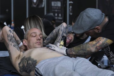 Brüksel, Belçika. 9 Kasım 2019. Uluslararası Brüksel Dövme Kongresi sırasında bir dövme sanatçısı bir kişiye dövme yaptırdı.