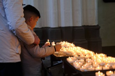 A worshiper light candles in church of Our Lady in Bruges, Belgium on Nov. 30, 2019. clipart