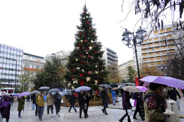 Yunanistan 'ın başkenti Atina' daki Syntagma meydanında 30 Aralık 2019 'da insanlar Noel ağacının önünde yürüyor.