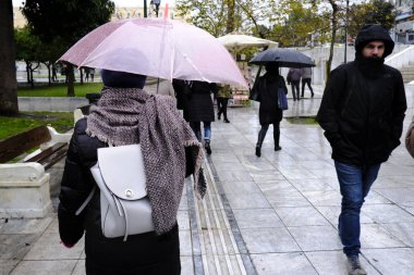 Yunanistan 'ın başkenti Atina' da 30 Aralık 2019 'da meydana gelen yağış sırasında yayalar kendilerini şemsiyelerle yağmurdan koruyorlar..