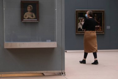 Ziyaretçiler, 19 Mayıs 2020 'de Belçika' nın Brüksel kentindeki Kraliyet Güzel Sanatlar Müzesi 'ndeki resimlere bakarken koronavirüsün yayılmasını önlemek için yüz maskesi takıyorlar..
