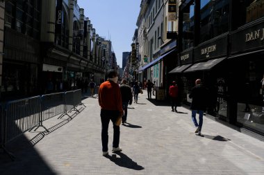 Yüz maskesi takan insanlar, 18 Mayıs 2020 'de Brüksel, Blegium' da Coronavirus, COVID-19 'un yayılmasını önlemek için tecrit kaldırılırken ticari caddede yavaş yavaş yürürler..