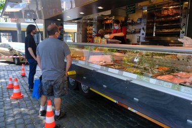 Koruyucu maske ve eldiven takan bir tavuk dükkanı çalışanı, 18 Mayıs 2020 'de Brüksel' deki açık hava pazarında Coronavirus (COVID-19) adlı roman salgınının ortasında tüketiciye hizmet vermektedir.).