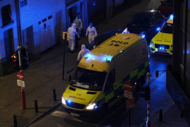 Korunma ekipmanı takan ilk yardım itfaiyecileri, 5 Mayıs 2020 'de Belçika' da Brüksel 'deki bir hastaneye ambulansla götürülmeden önce COVID-19 taşıdığından şüphelenilen bir hastayı taşıyorlar..