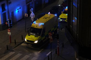 Korunma ekipmanı takan ilk yardım itfaiyecileri, 5 Mayıs 2020 'de Belçika' da Brüksel 'deki bir hastaneye ambulansla götürülmeden önce COVID-19 taşıdığından şüphelenilen bir hastayı taşıyorlar..