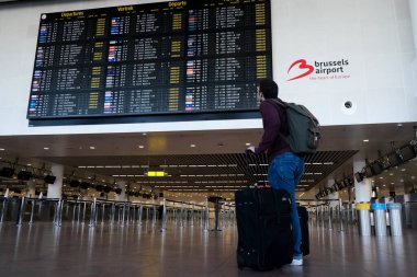 Yolcular, 15 Mayıs 2020 'de Brüksel, Belçika yakınlarındaki Zaventem Uluslararası Havalimanı' ndaki uçuşların çoğunun iptal edildiği kalkış biletlerini kontrol ediyorlar..