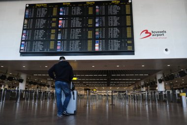 Yolcular, 15 Mayıs 2020 'de Brüksel, Belçika yakınlarındaki Zaventem Uluslararası Havalimanı' ndaki uçuşların çoğunun iptal edildiği kalkış biletlerini kontrol ediyorlar..