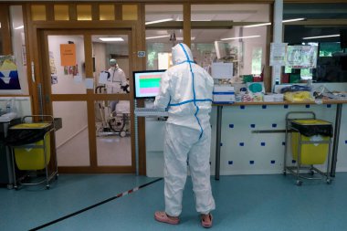 5 Mayıs 2020 'de Belçika' daki Liege Üniversitesi Hastanesi 'nde COVID-19 hastalarına yardım etmeden önce bir sağlık çalışanı kişisel koruyucu ekipman (PPE) giyer.