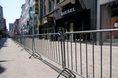 9 Mayıs 2020 'de Brüksel' in merkezinde çitlerle ayrılmış bir alışveriş caddesi olan Rue Neuve 'de koruyucu maske takan insanlar yürüyor. Belçika 'daki dükkanlar 11 Mayıs 2020' de yeniden açılacak..