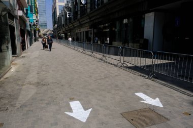 9 Mayıs 2020 'de Brüksel' in merkezinde çitlerle ayrılmış bir alışveriş caddesi olan Rue Neuve 'de koruyucu maske takan insanlar yürüyor. Belçika 'daki dükkanlar 11 Mayıs 2020' de yeniden açılacak..