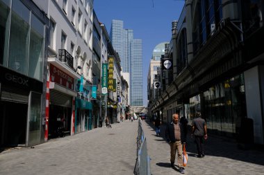 9 Mayıs 2020 'de Brüksel' in merkezinde çitlerle ayrılmış bir alışveriş caddesi olan Rue Neuve 'de koruyucu maske takan insanlar yürüyor. Belçika 'daki dükkanlar 11 Mayıs 2020' de yeniden açılacak..