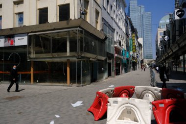 9 Mayıs 2020 'de Brüksel' in merkezinde çitlerle ayrılmış bir alışveriş caddesi olan Rue Neuve 'de koruyucu maske takan insanlar yürüyor. Belçika 'daki dükkanlar 11 Mayıs 2020' de yeniden açılacak..