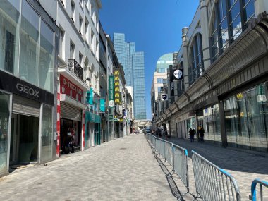 9 Mayıs 2020 'de Brüksel' in merkezinde çitlerle ayrılmış bir alışveriş caddesi olan Rue Neuve 'de koruyucu maske takan insanlar yürüyor. Belçika 'daki dükkanlar 11 Mayıs 2020' de yeniden açılacak..